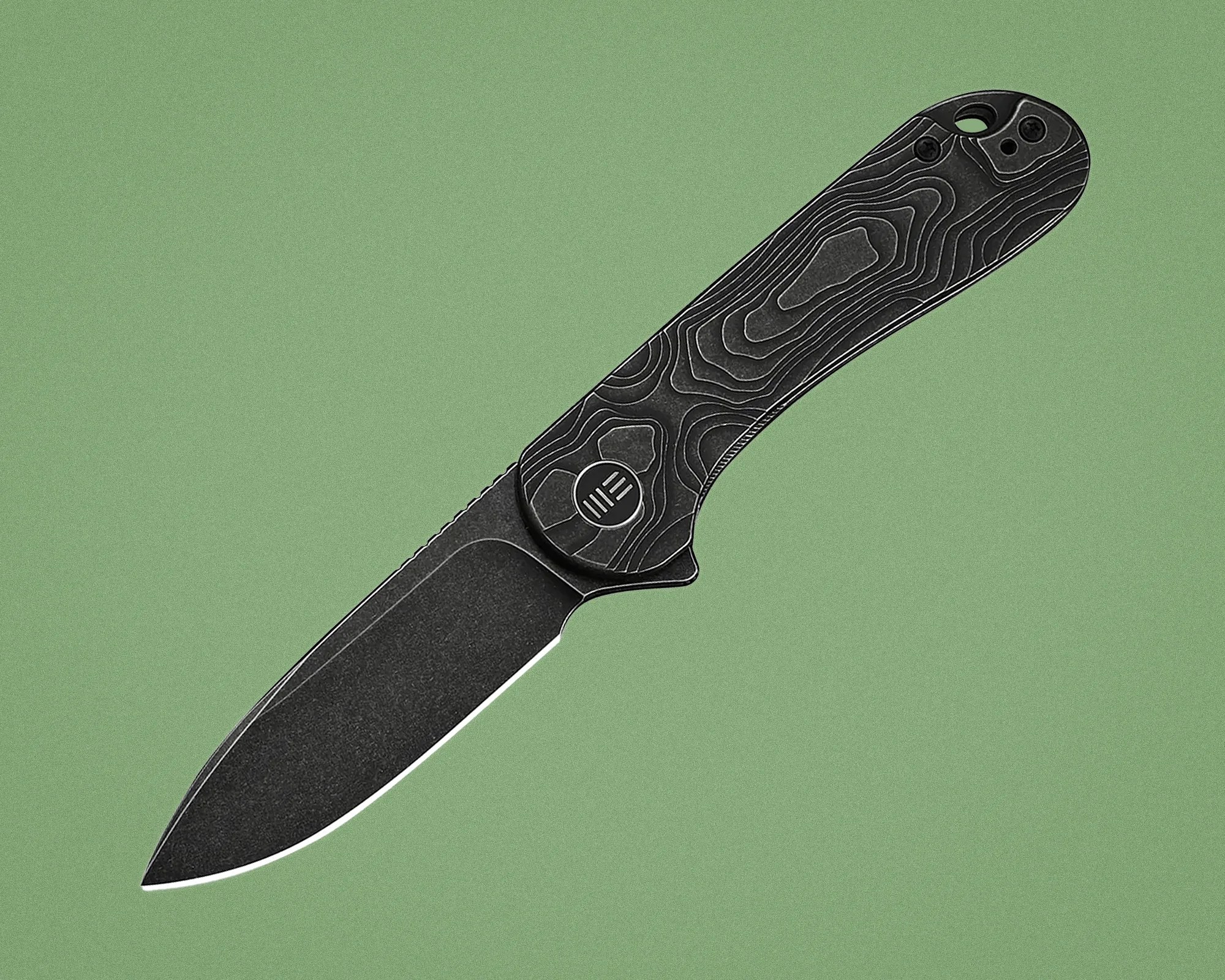 Black folding knife with textured handle featuring topographic map design on a green background.