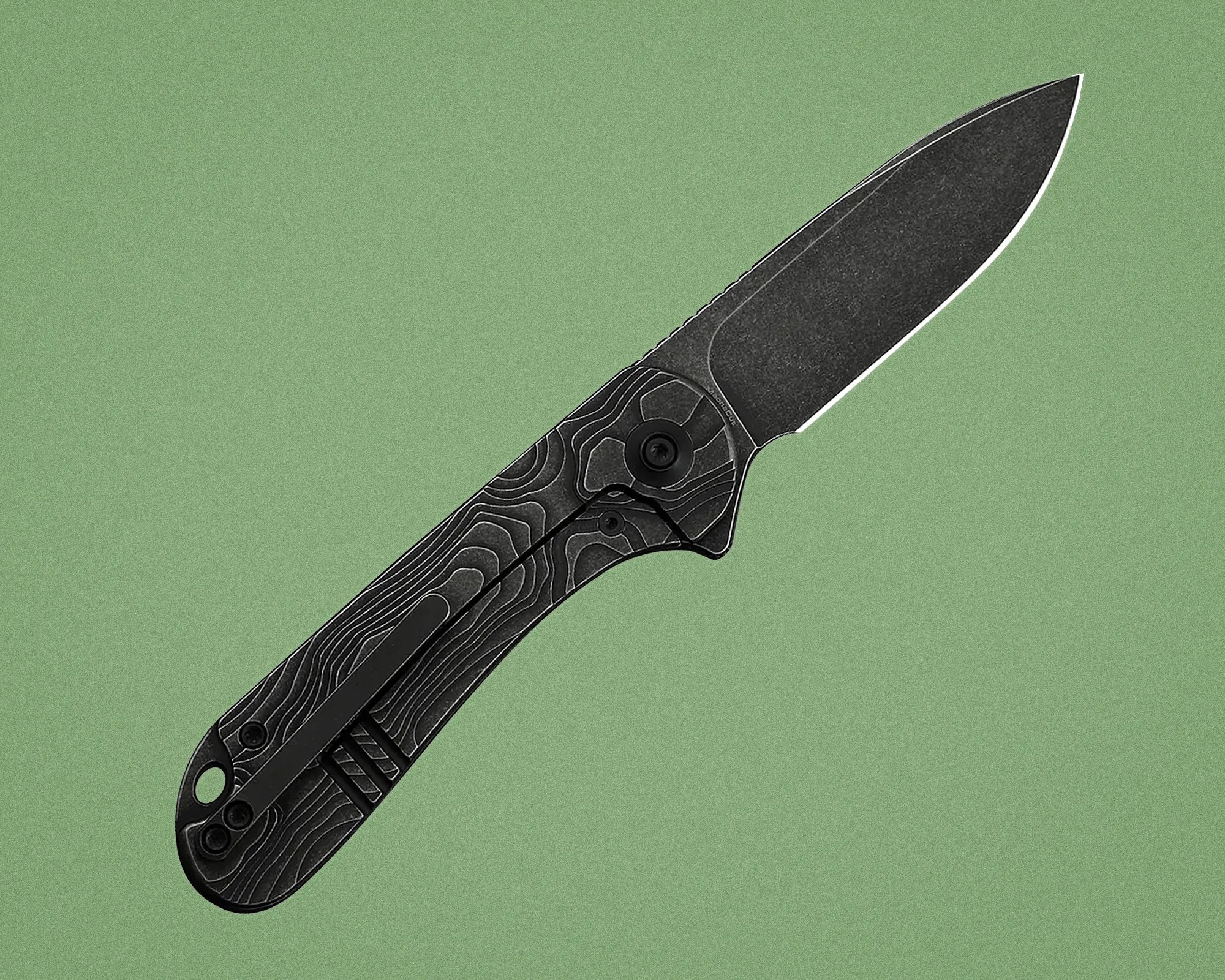 Black folding knife with textured handle and partially serrated blade on green background.