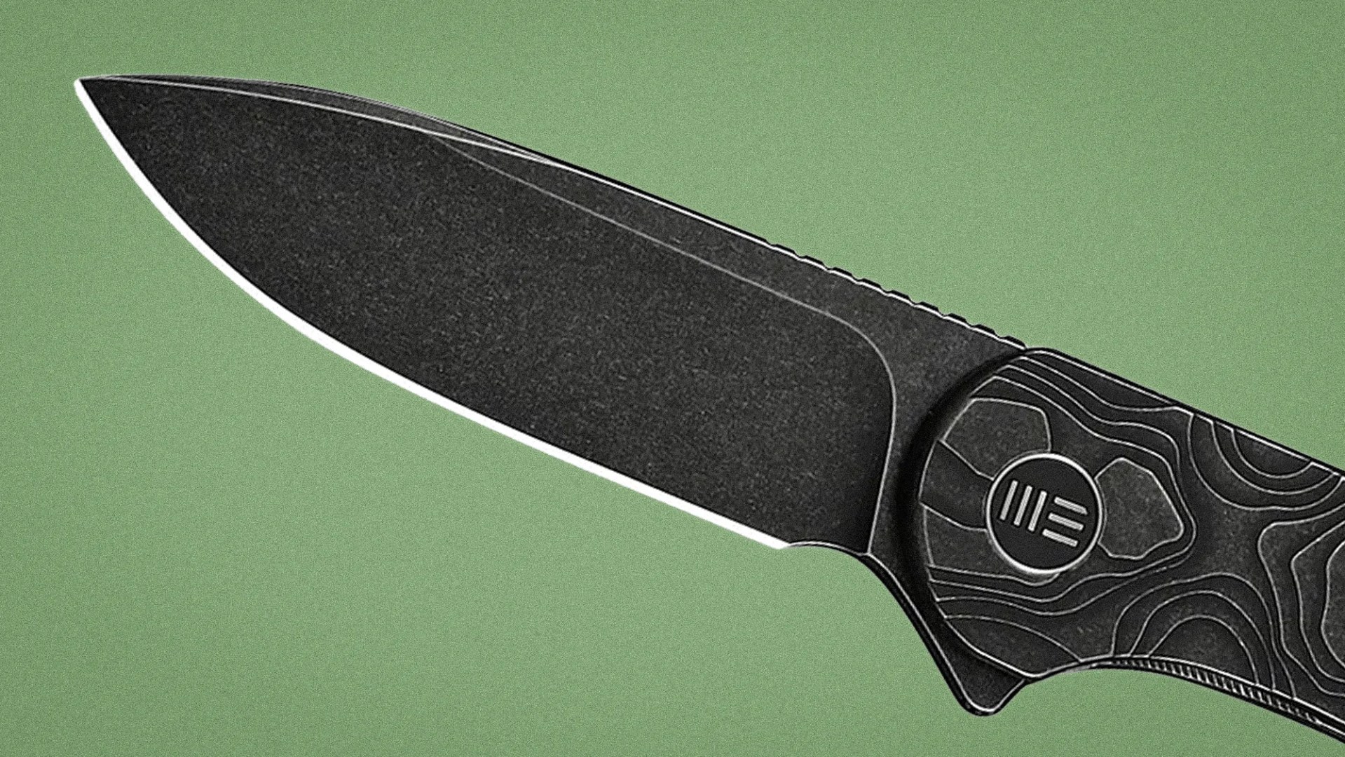 Black tactical knife blade with textured handle featuring contour line design on green background.