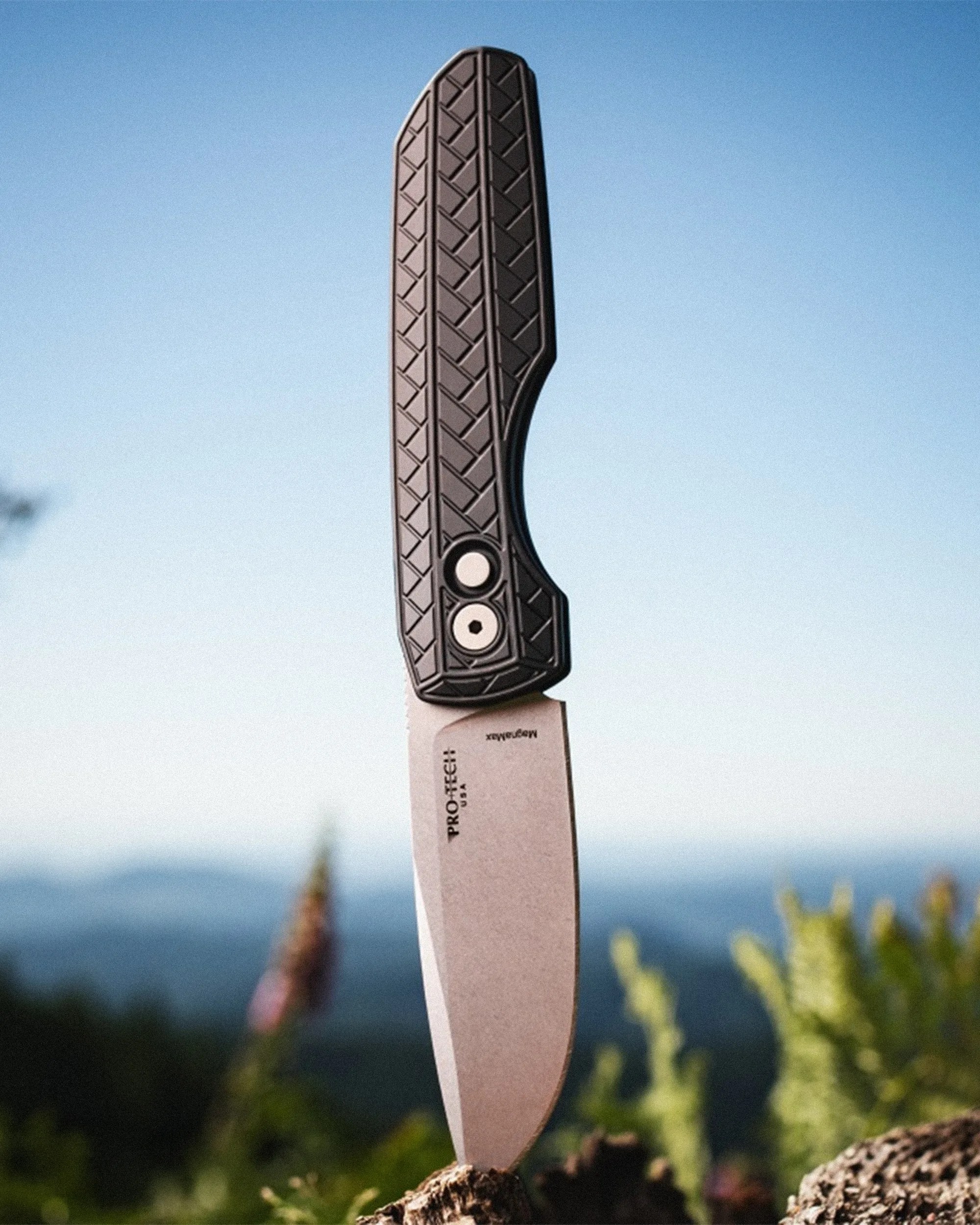 Knife with a textured black handle and stonewashed blade stuck in a tree stump outdoors.