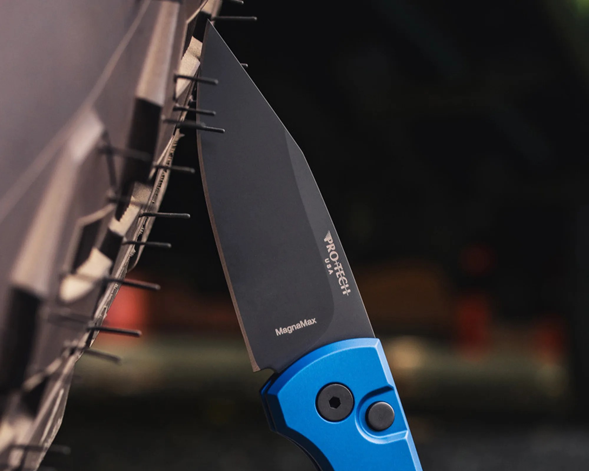 Black Pro-Tech MagnaMax folding knife blade with blue handle inserted into a wooden rack.