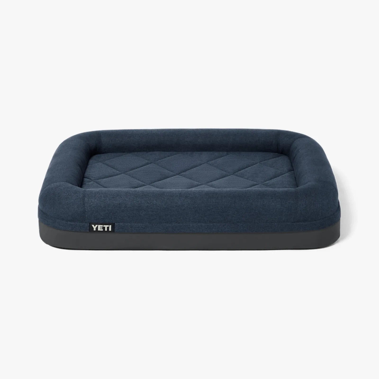 Rectangular navy blue quilted dog bed with raised cushioned sides and a black base labeled YETI.