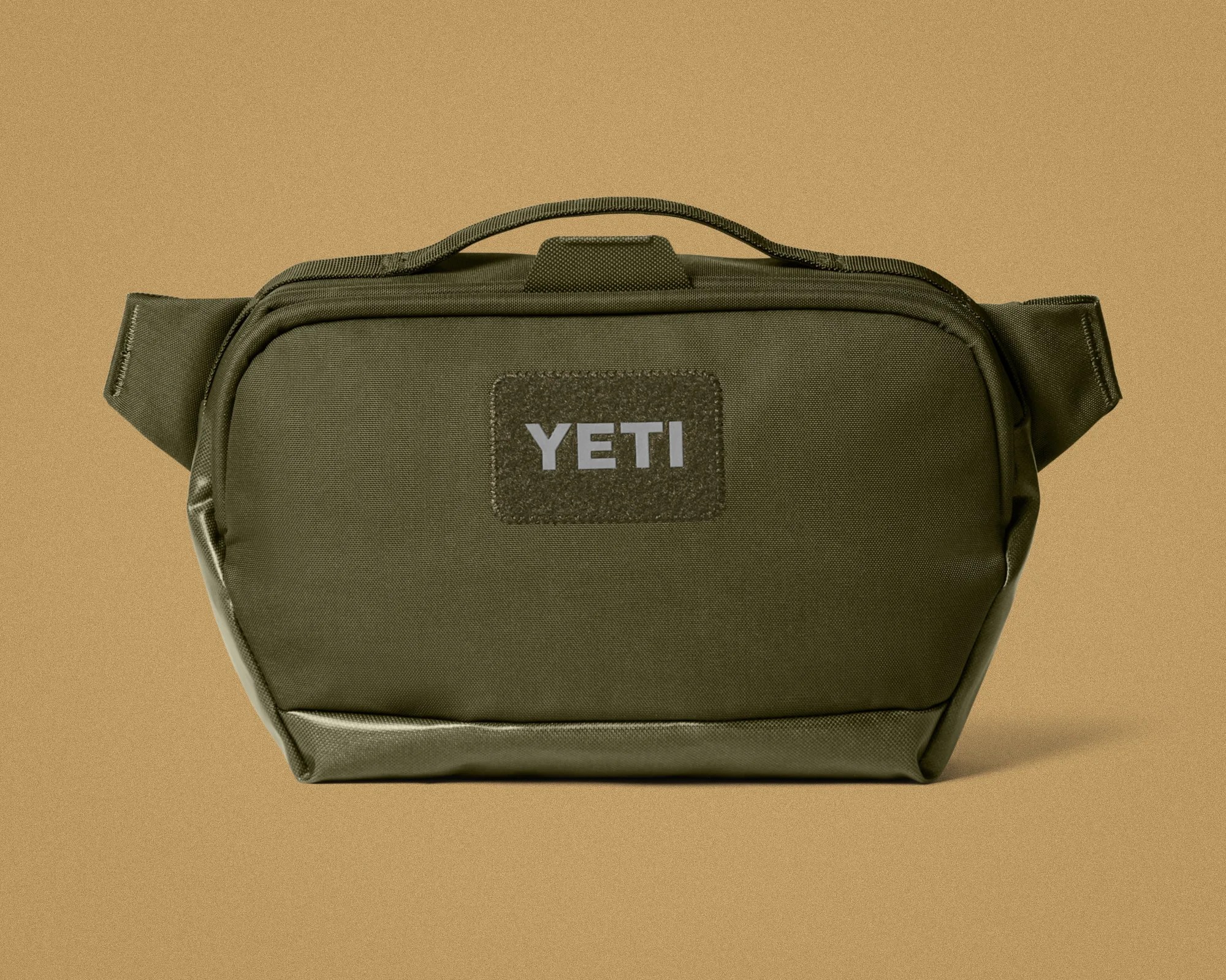 Olive green YETI soft-sided bag with top handle on a tan background.