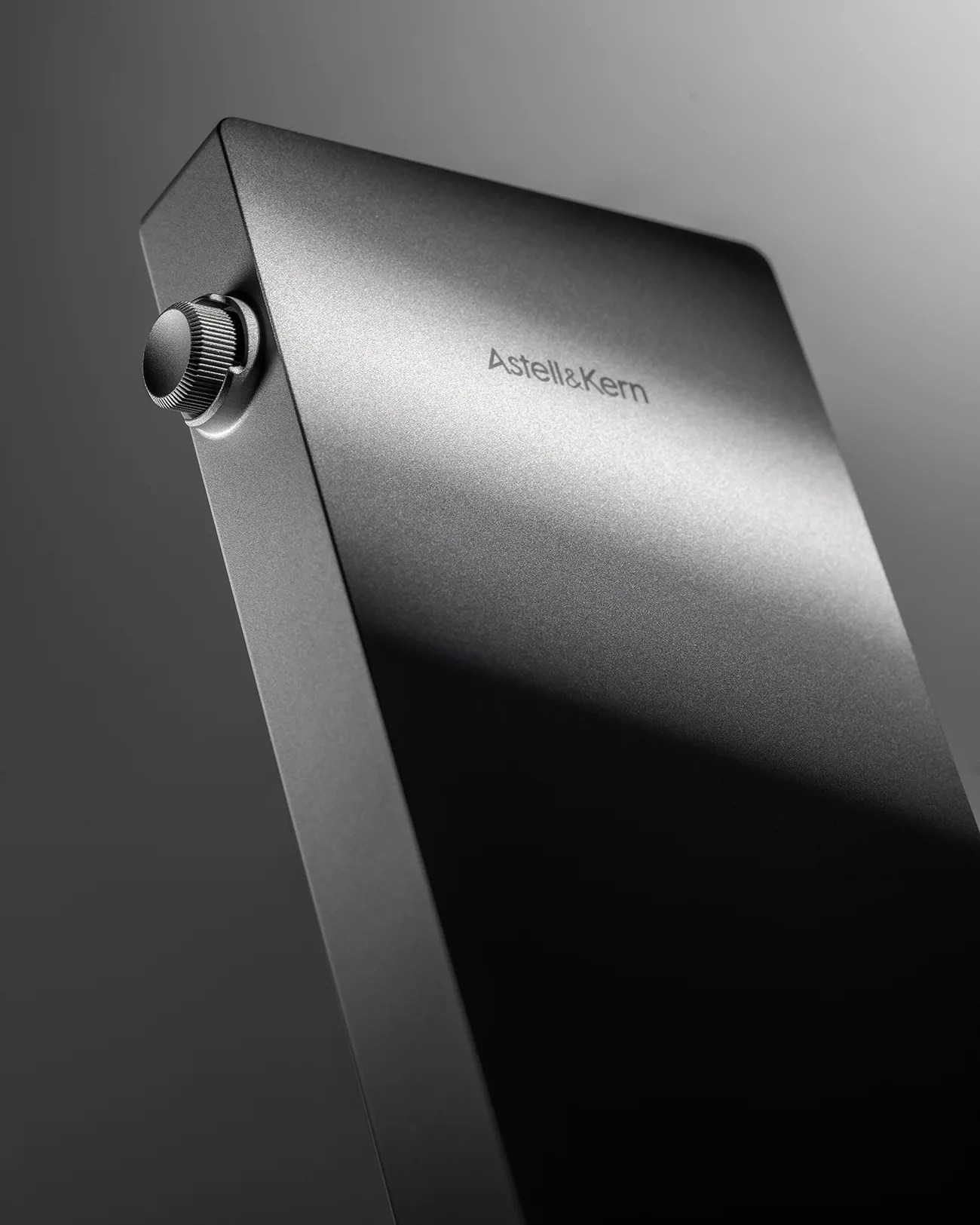 Matte black rectangular electronic device with a textured volume knob and "Astell&Kern" logo on the surface.
