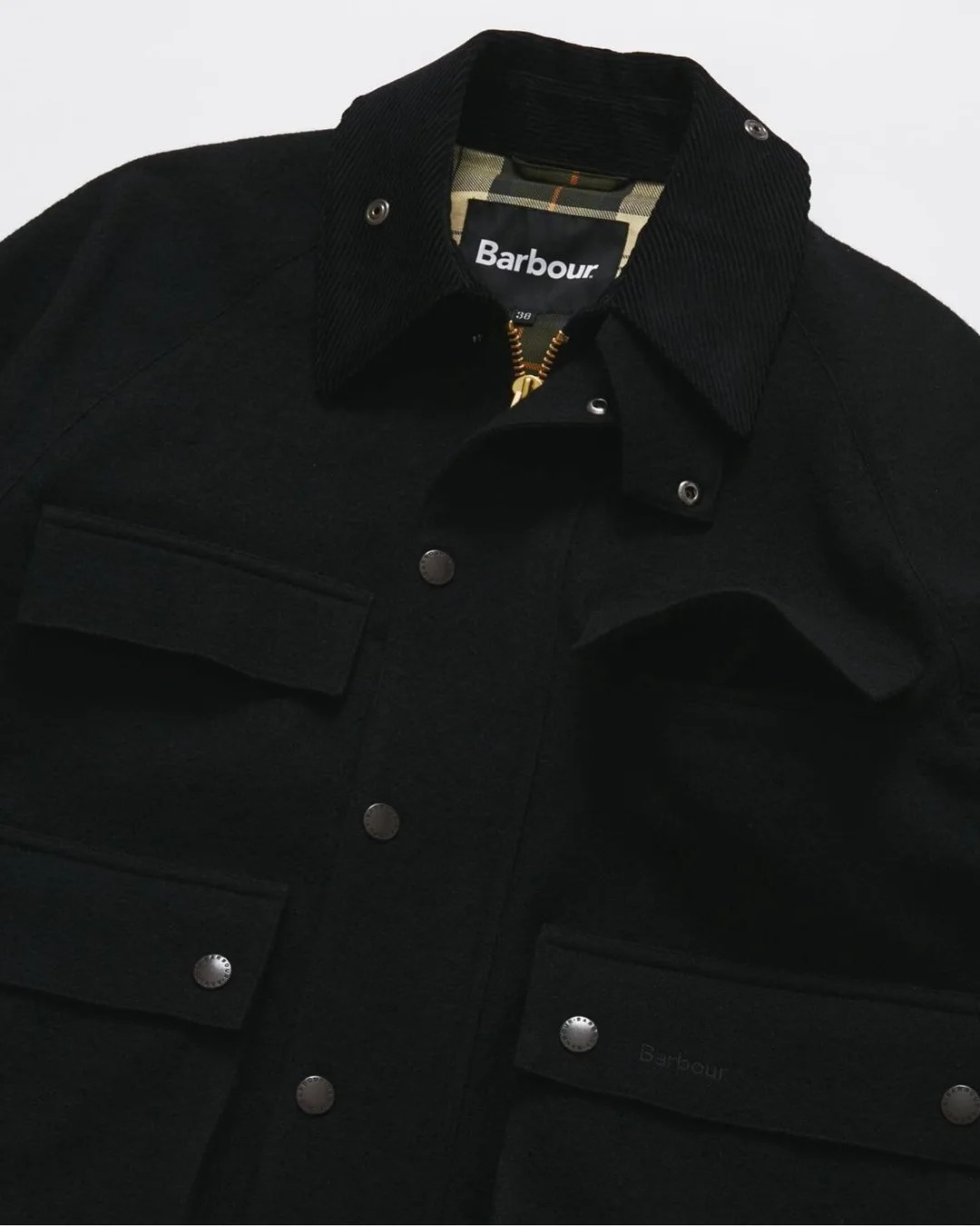 Black Barbour jacket with corduroy collar, snap buttons, and flap pockets.