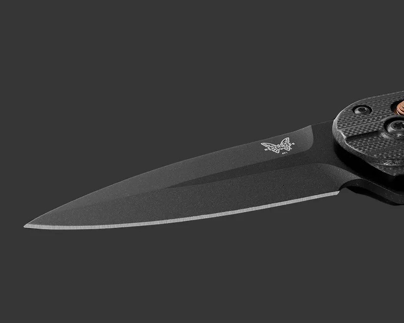 Black folding knife with a textured handle and a partially serrated blade on a dark background.