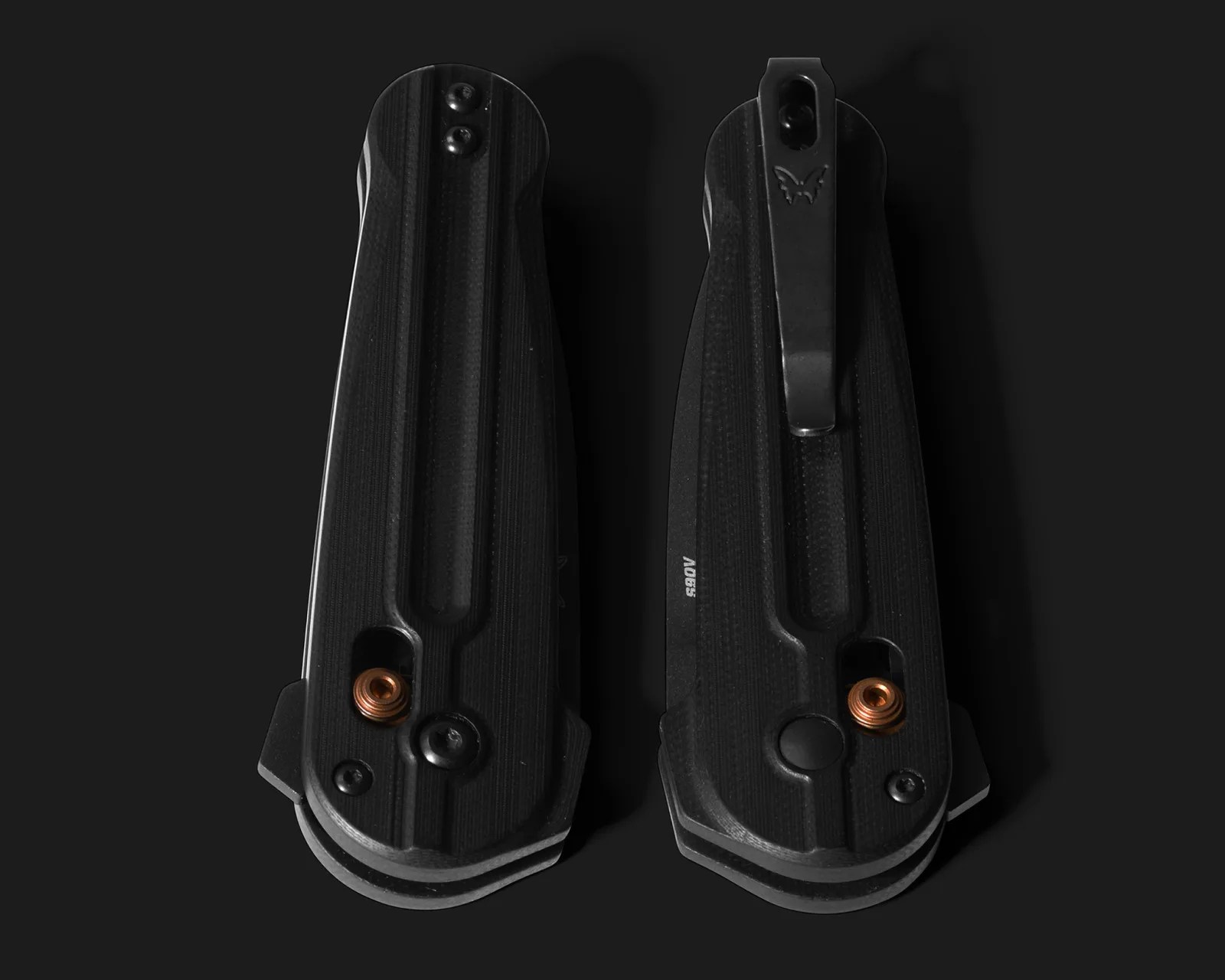 Two black folding knives with textured handles and copper-colored pivot screws, shown from the back on a black background.
