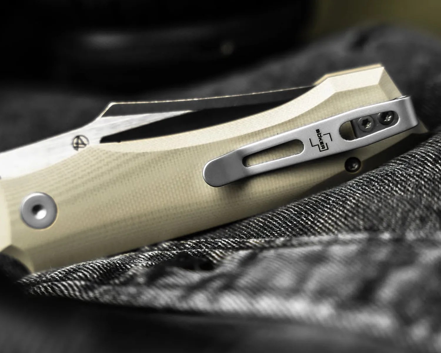 Close-up of a beige-handled folding knife with a silver pocket clip engraved with the Böker logo.
