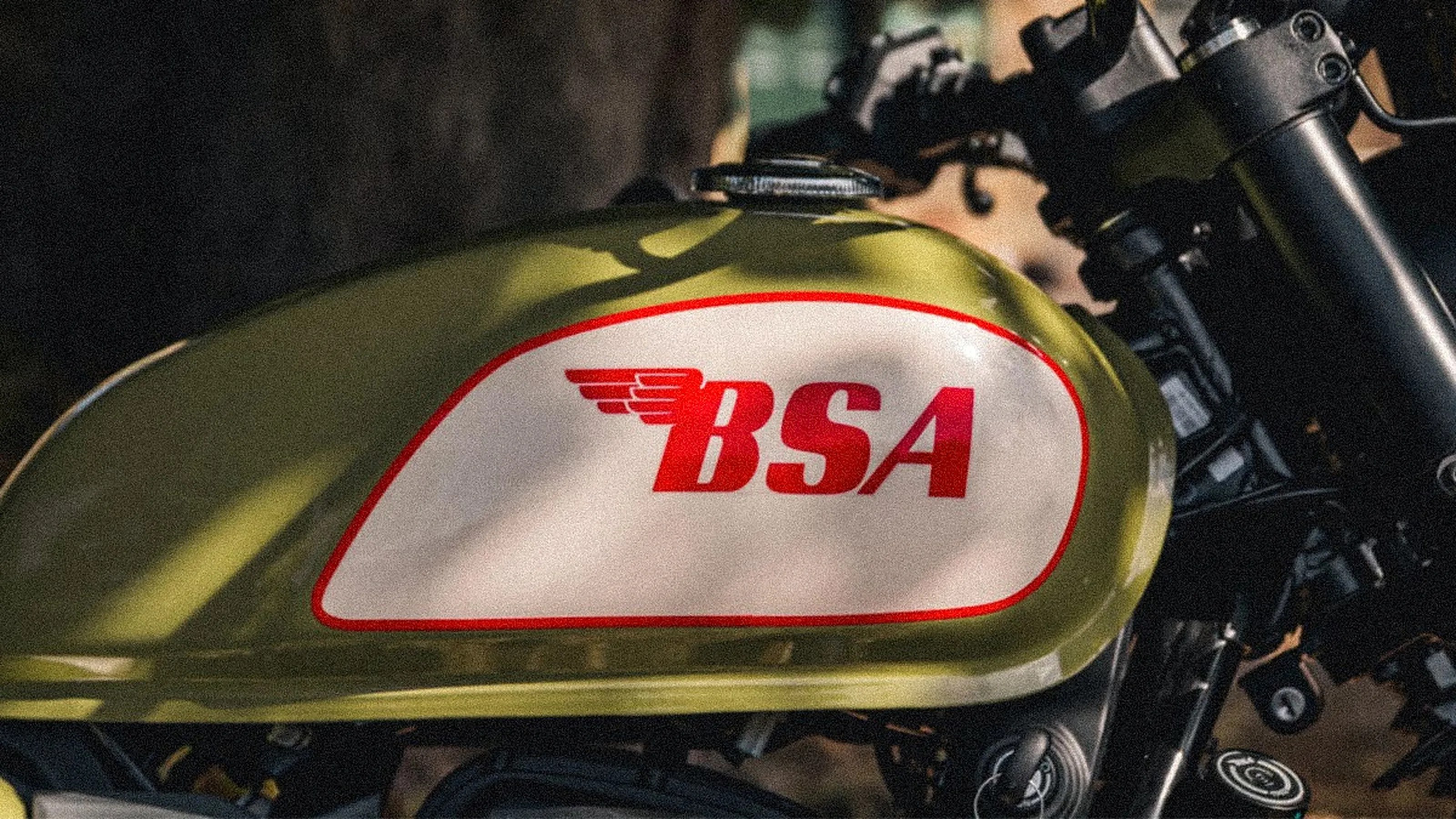 Olive green motorcycle fuel tank with a white panel and red "BSA" logo.
