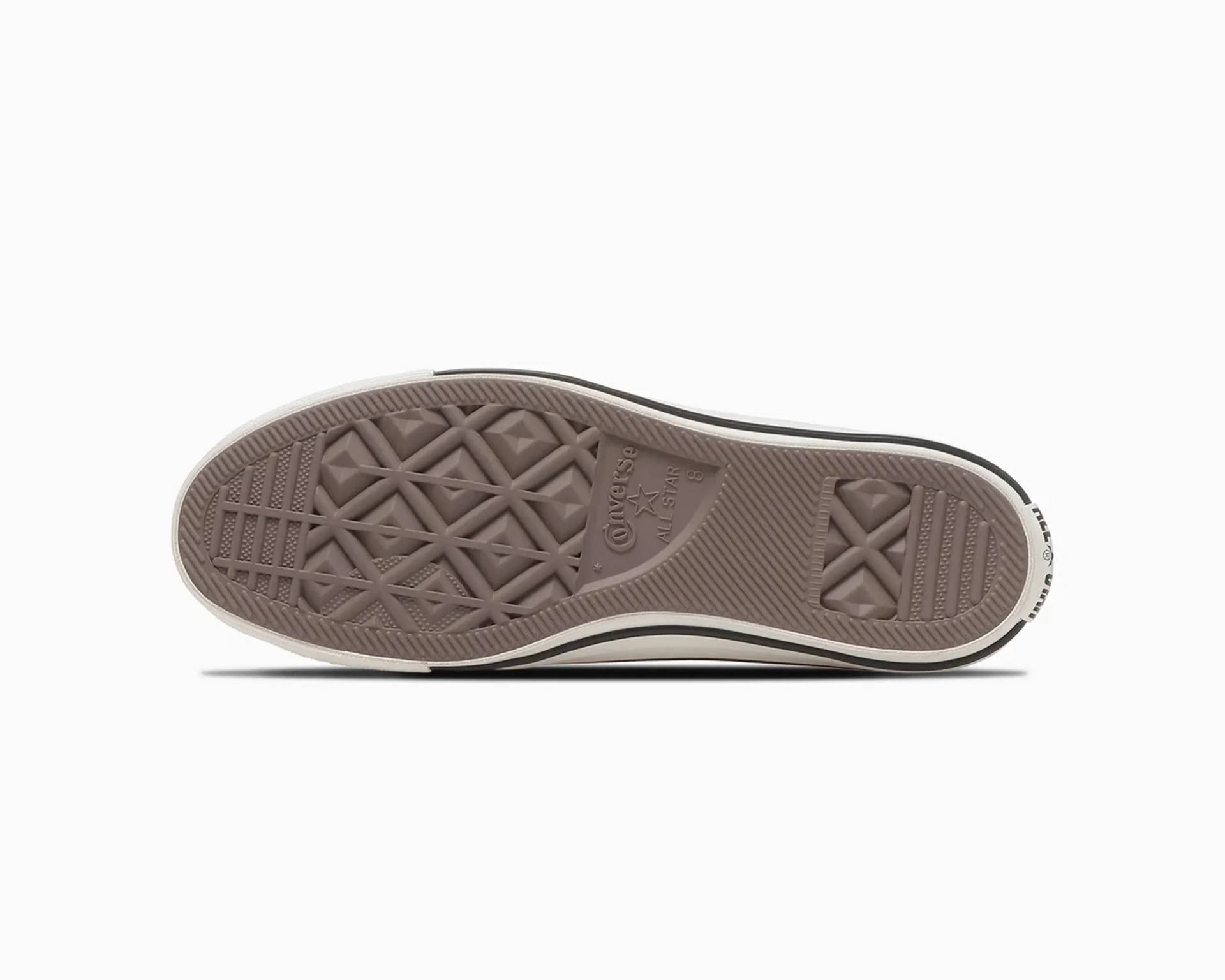 Brown rubber sole of a Converse All Star sneaker with a white midsole and black stripe.