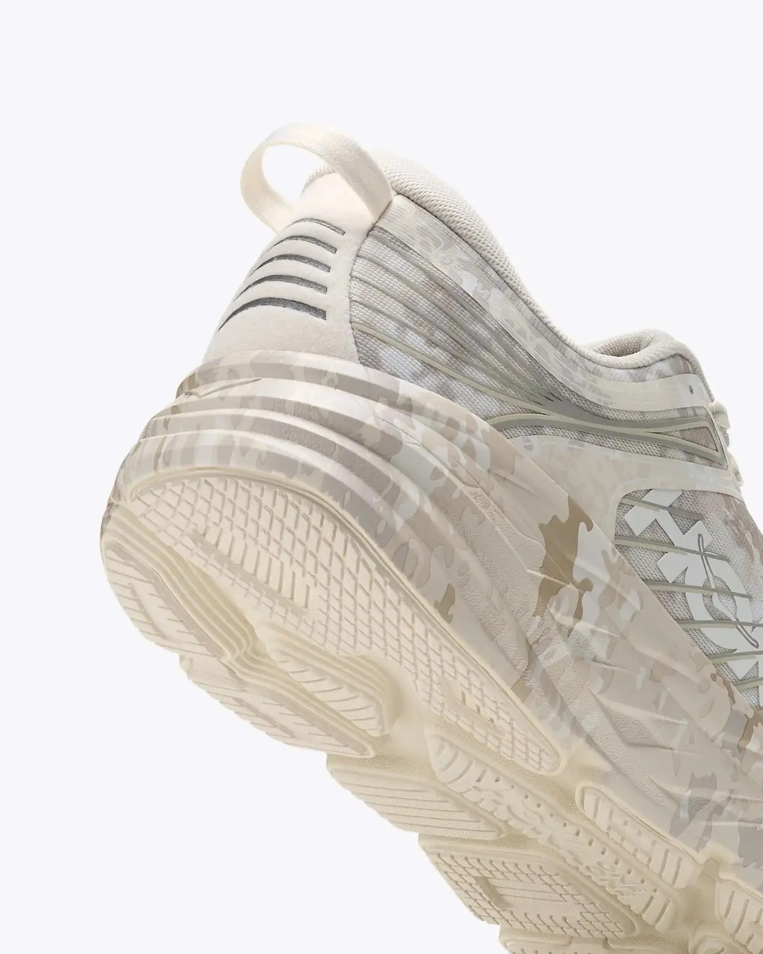 Beige and cream athletic shoe with textured sole and pull tab at heel.