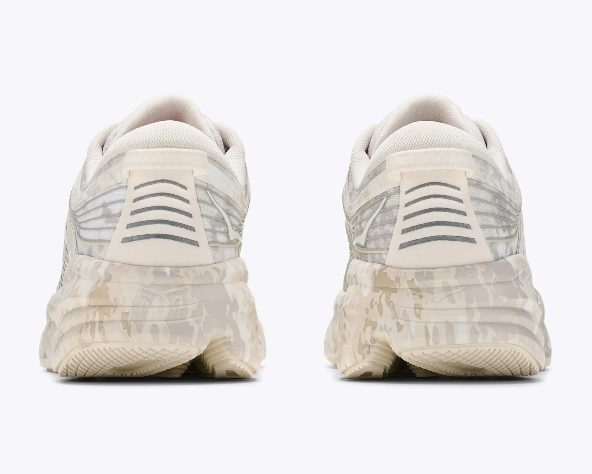 Pair of beige and white sneakers with camo-patterned soles viewed from the back.