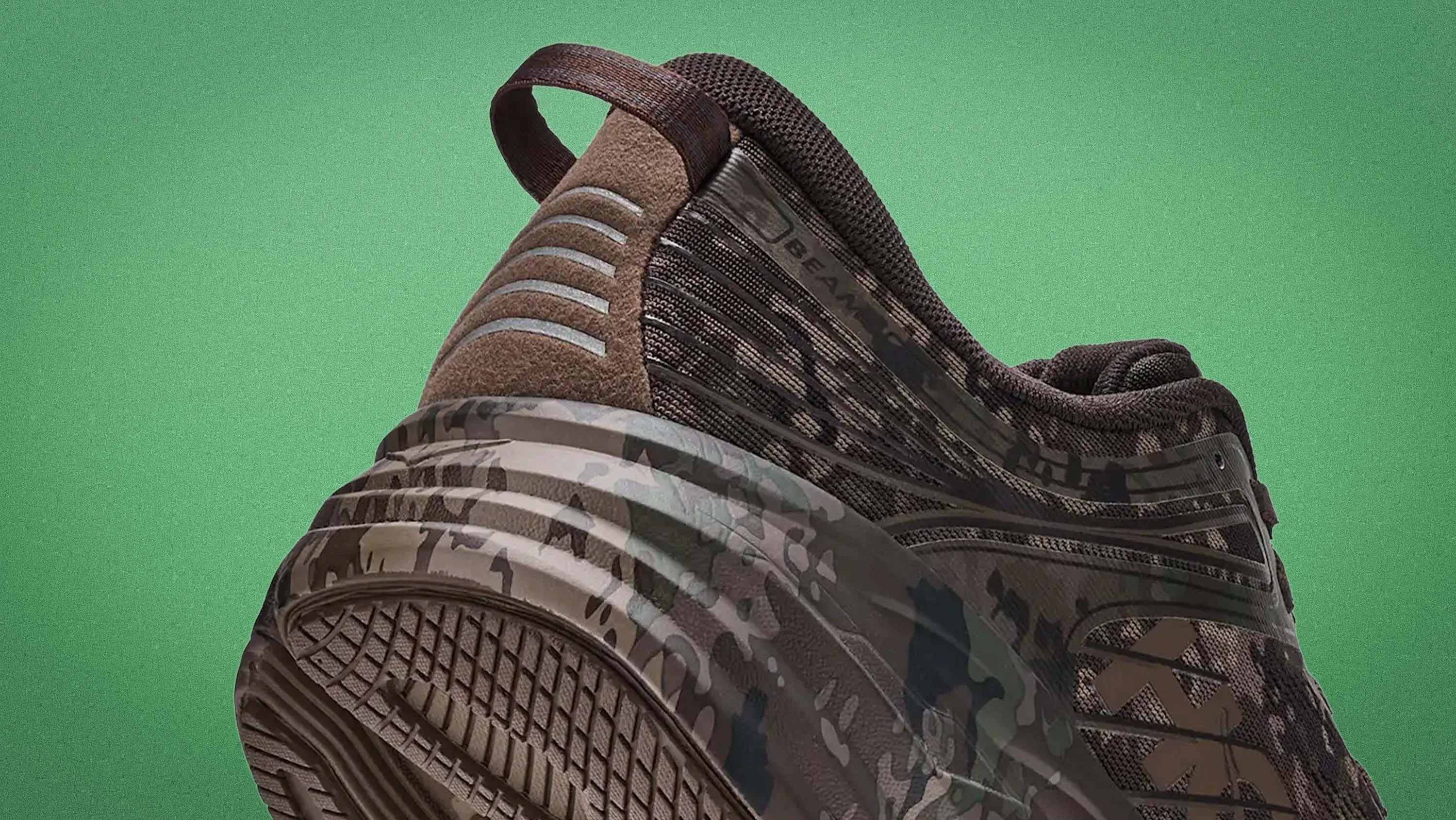 Close-up of a brown and black camo-patterned sneaker heel with textured sole and pull tab against a green background.