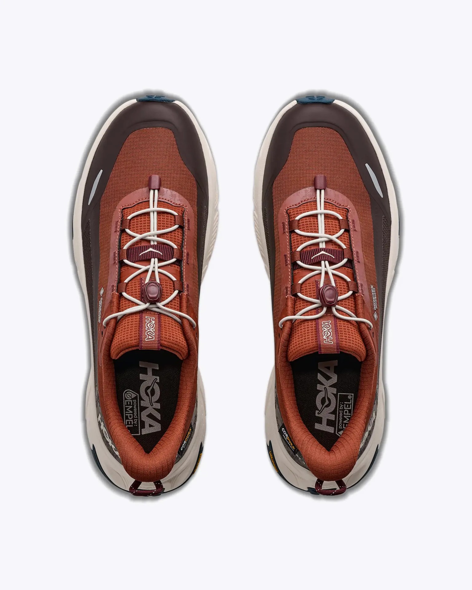 Pair of rust orange and dark brown Hoka running shoes with white elastic laces and beige midsoles viewed from above.