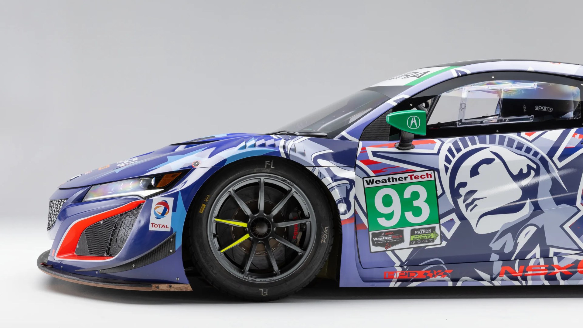 Blue and white race car with number 93, green side mirror, and stylized face graphic on the door.