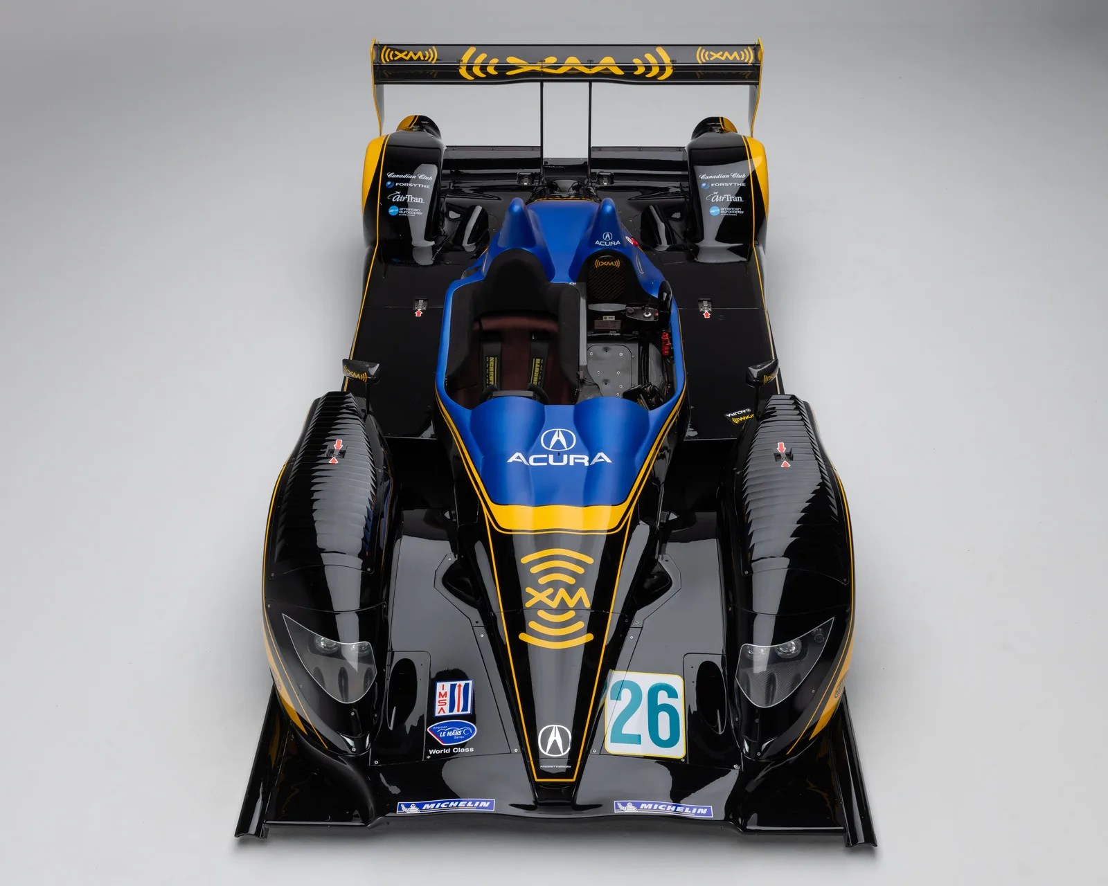 Black and blue Acura race car with yellow accents and number 26 on a gray background.