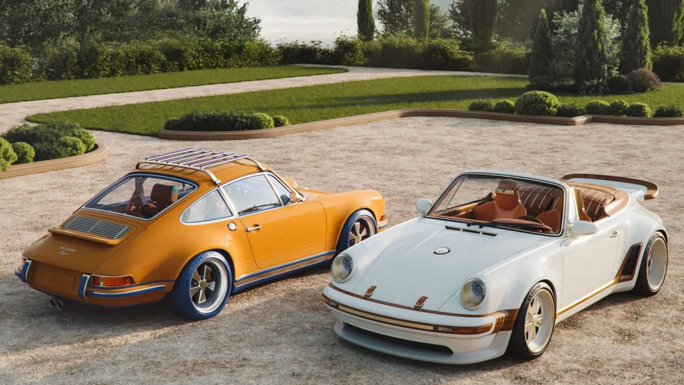 Two vintage Porsche cars, one orange with a roof rack and blue tires, and one white convertible with brown leather interior, parked on a gravel driveway.