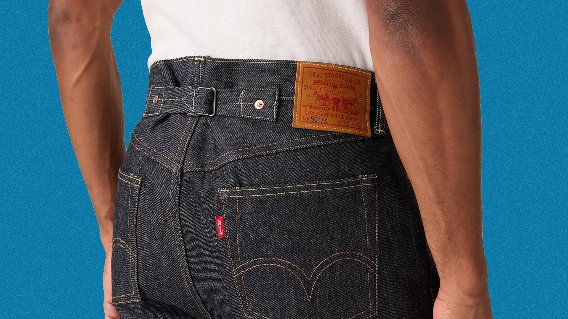 Close-up of dark blue Levi's 501 XX denim jeans back with leather patch and adjustable buckle strap.