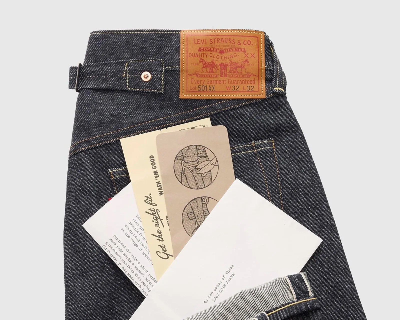 Folded dark blue Levi's 501 XX jeans with leather brand patch and care instruction cards in back pocket.