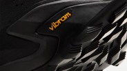 Close-up of a black shoe sole with textured tread and an orange "vibram" logo.