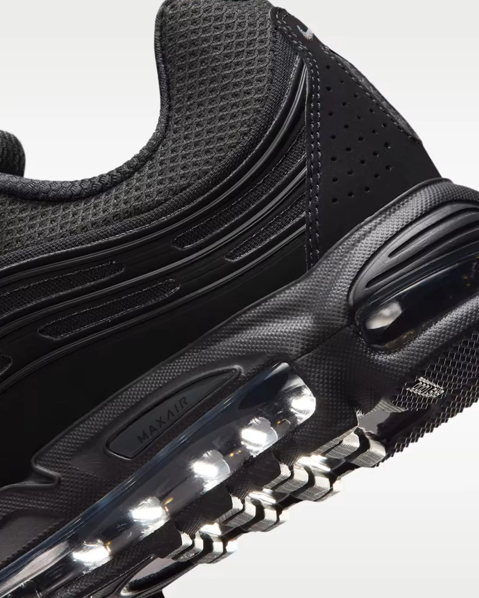 Close-up of a black sneaker with mesh upper, Max Air cushioning, and textured sole.