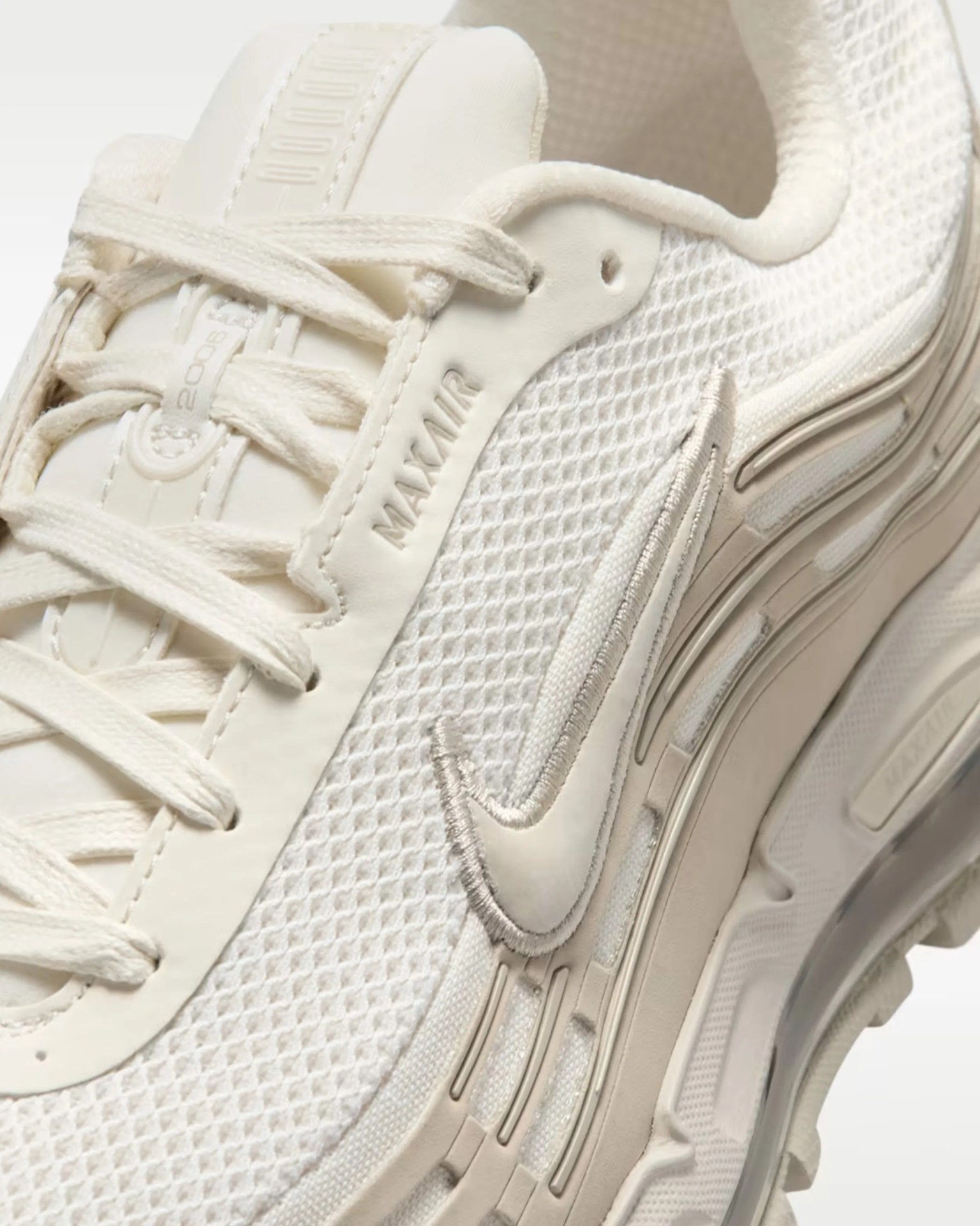 Close-up of a cream-colored Nike Air Max sneaker with mesh upper and embroidered swoosh logo.