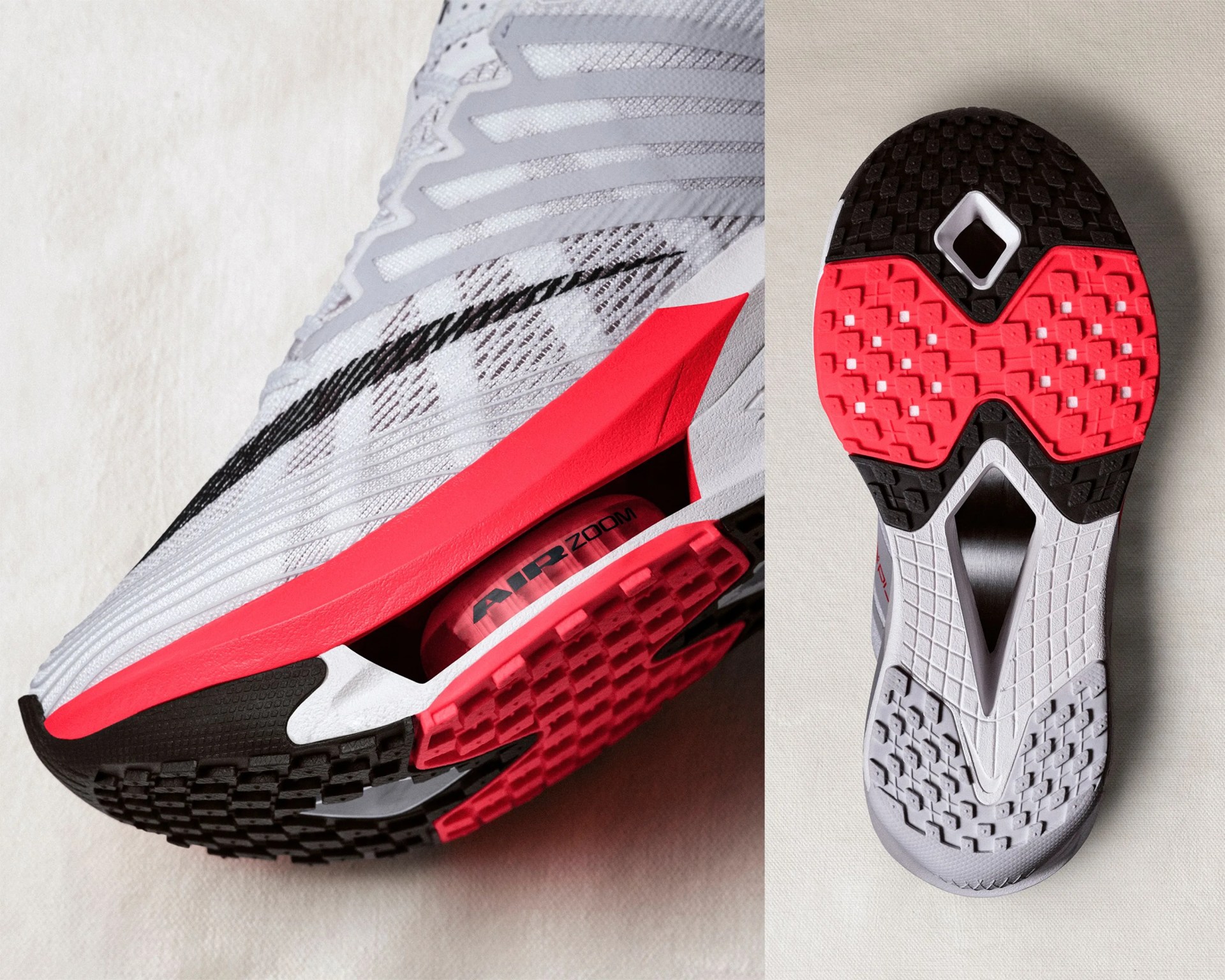 Close-up of a white and gray running shoe with black and red sole, showing side mesh and bottom tread pattern.