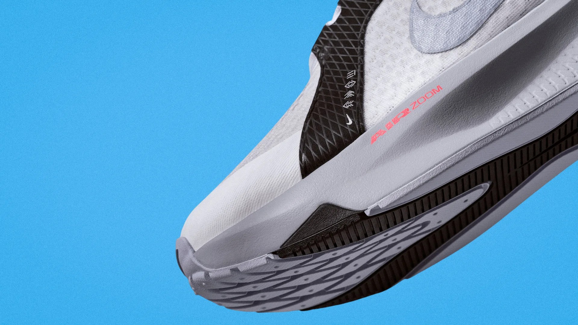 Close-up of a white and black Nike Air Zoom shoe sole against a blue background.