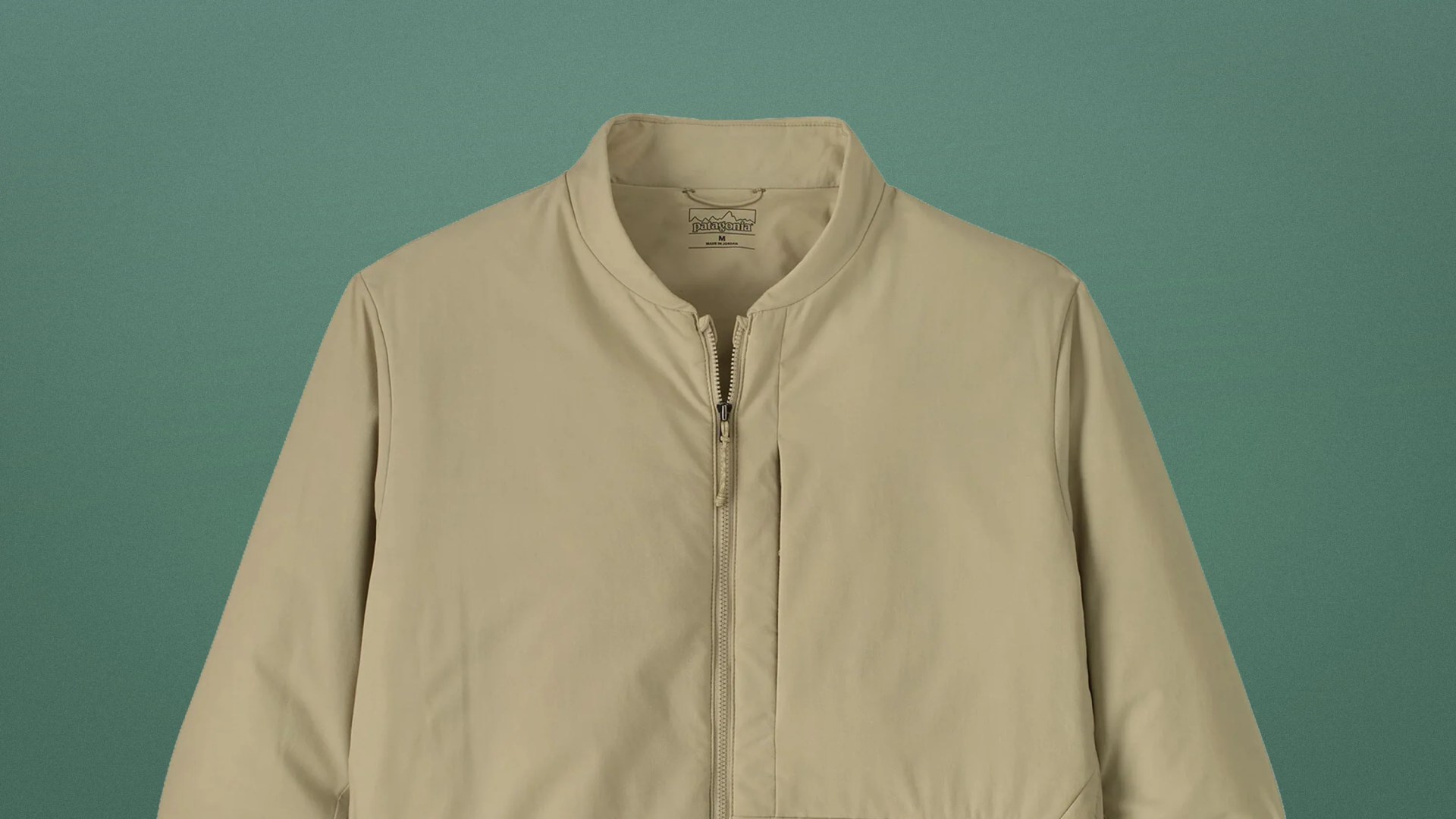 Beige Patagonia jacket with a front zipper and a stand collar against a green background.