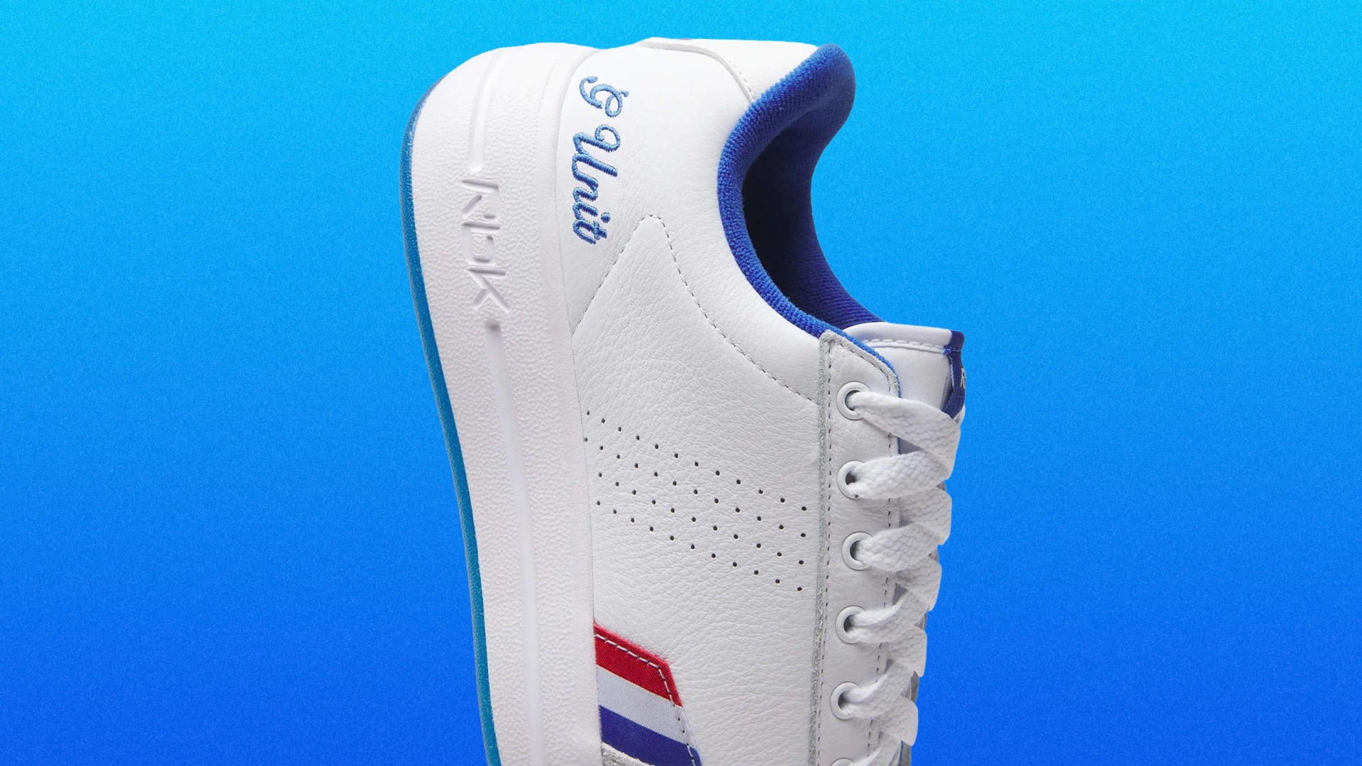 White leather sneaker with blue and red stripes, blue inner lining, and "PG Unit" embroidered on the heel.