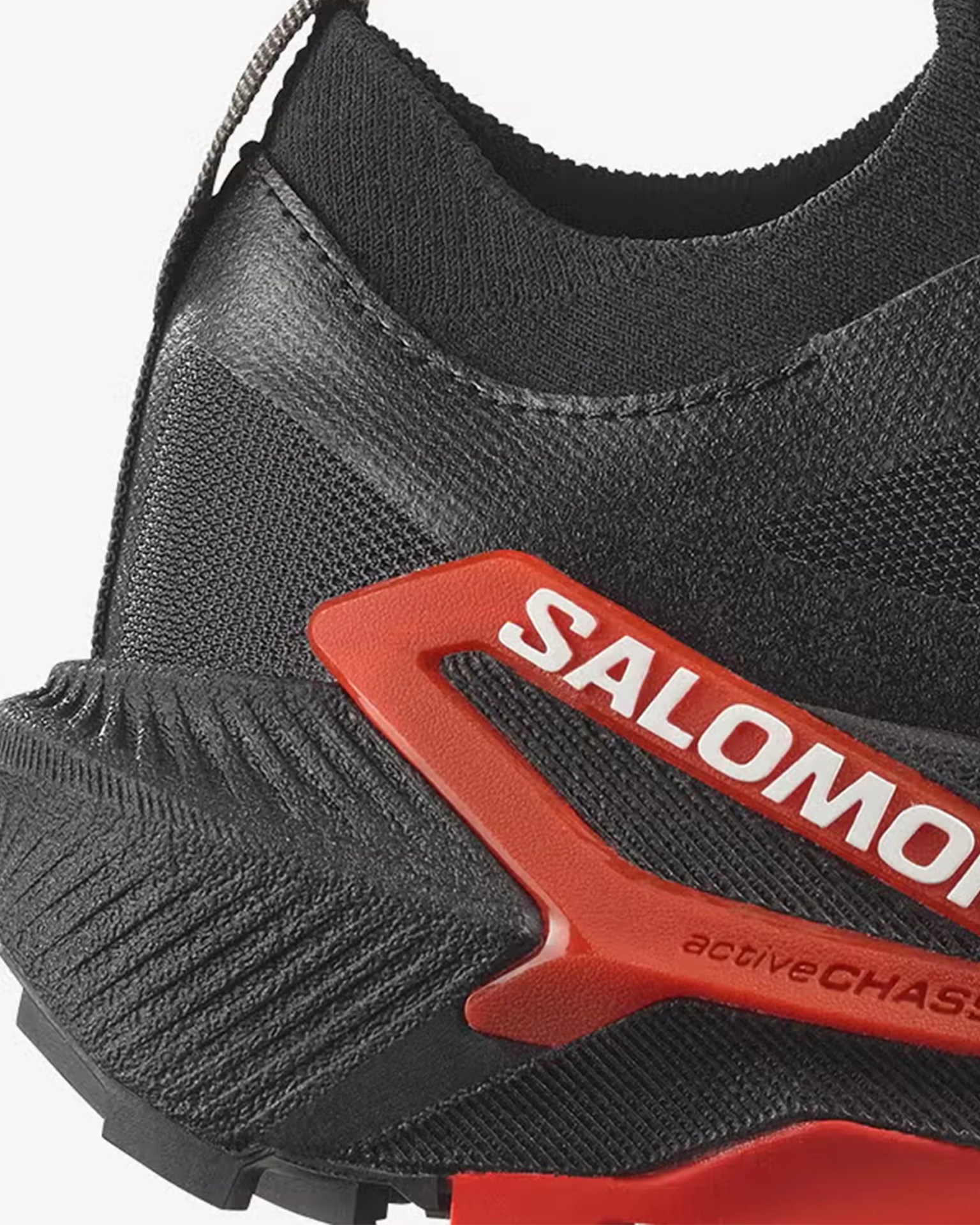 Close-up of black Salomon shoe with red plastic support and knit fabric upper.