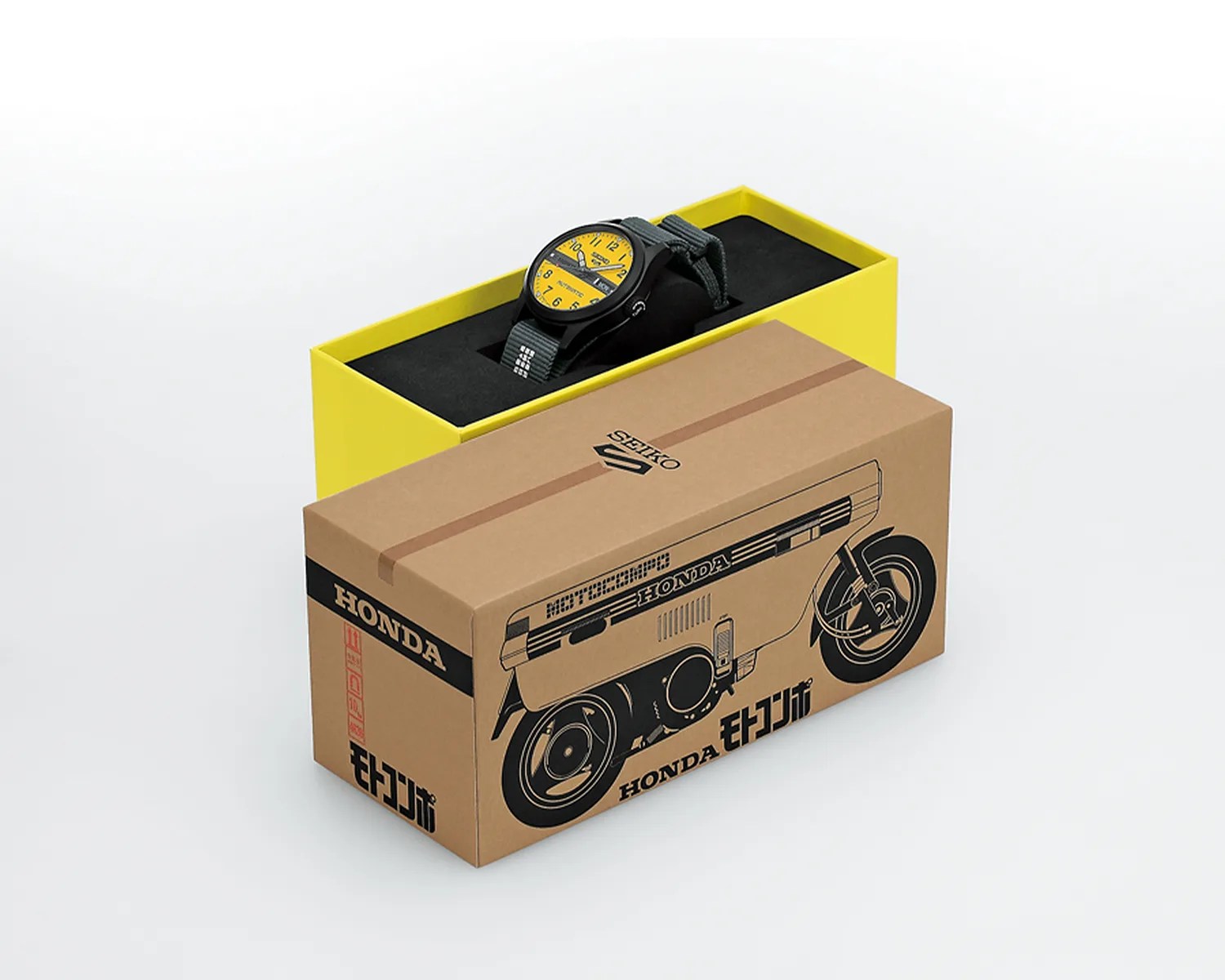 Black Seiko wristwatch with yellow dial and gray fabric strap in a yellow box with a brown Honda-themed outer box.