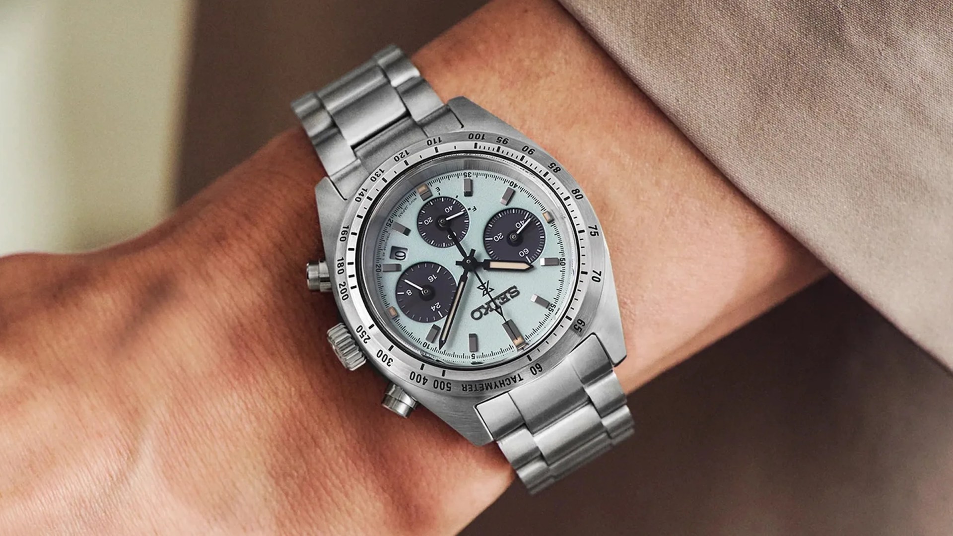 Silver Seiko chronograph wristwatch with light blue dial and three black subdials on a metal bracelet.