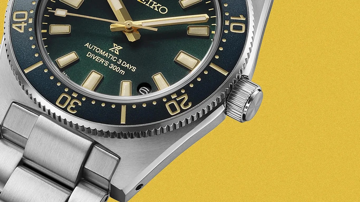 Close-up of a Seiko diver's watch with a green dial, gold-tone markers, and a stainless steel bracelet on a yellow background.