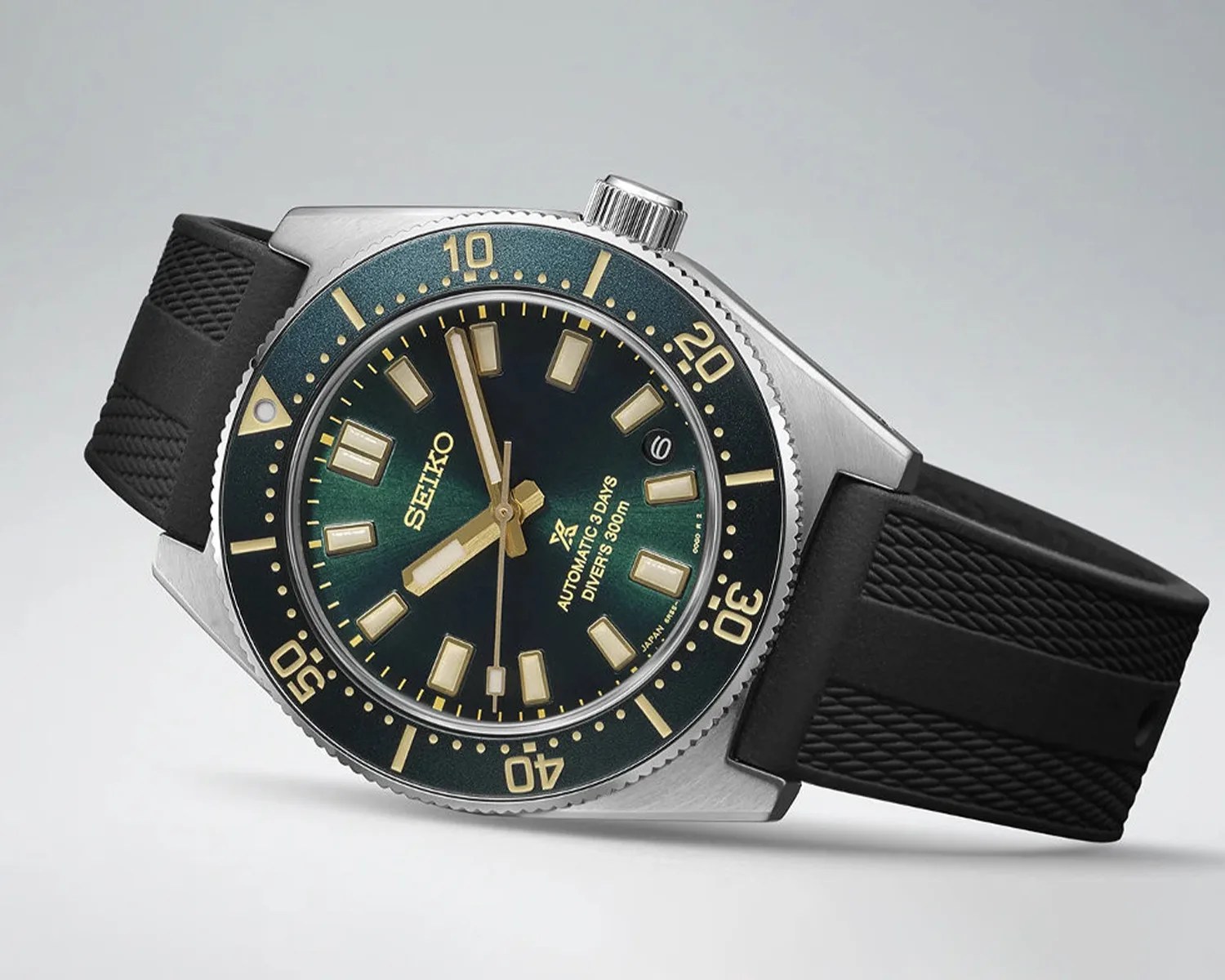 Seiko automatic diver's watch with black dial, gold markers, rotating bezel, and black textured rubber strap.