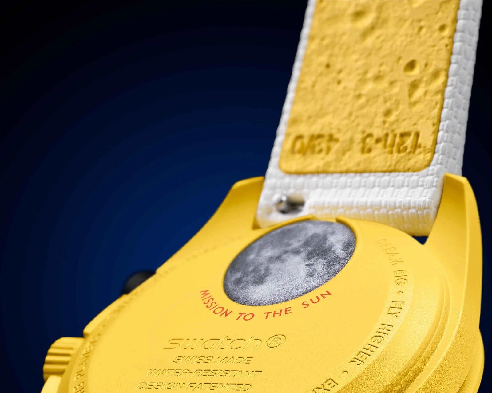 Close-up of the back of a yellow Swatch watch with a moon image and red text "MISSION TO THE SUN.