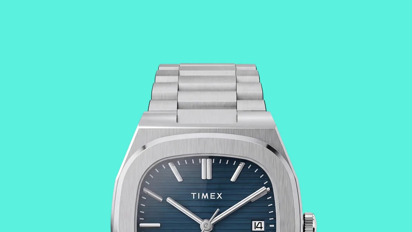 Silver stainless steel Timex wristwatch with a blue textured dial and date display on a turquoise background.