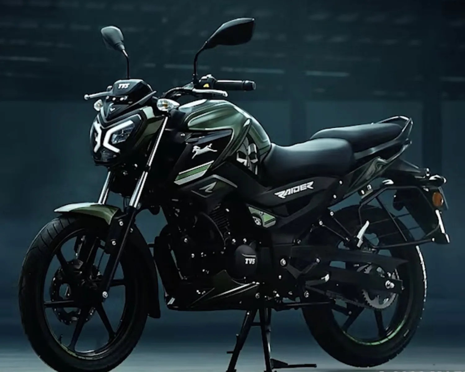 Matte green and black TVS Raider motorcycle with LED headlights and sporty design on a stand.
