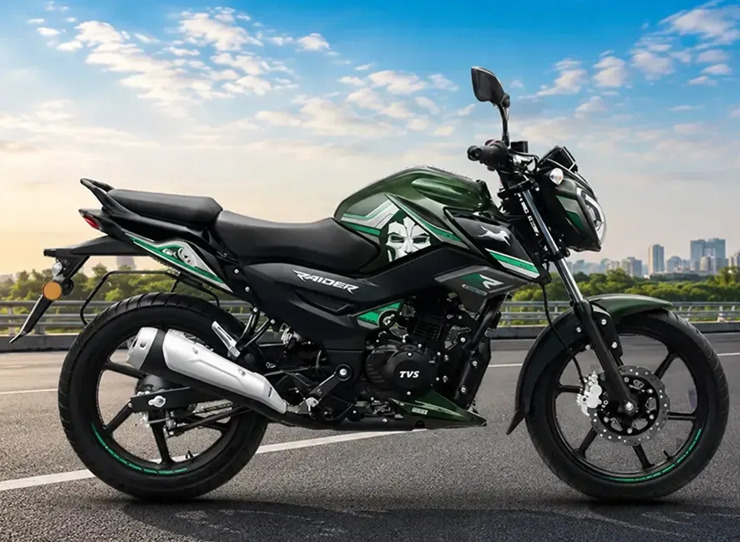 Green and black TVS Raider motorcycle parked on a road with city skyline in the background.