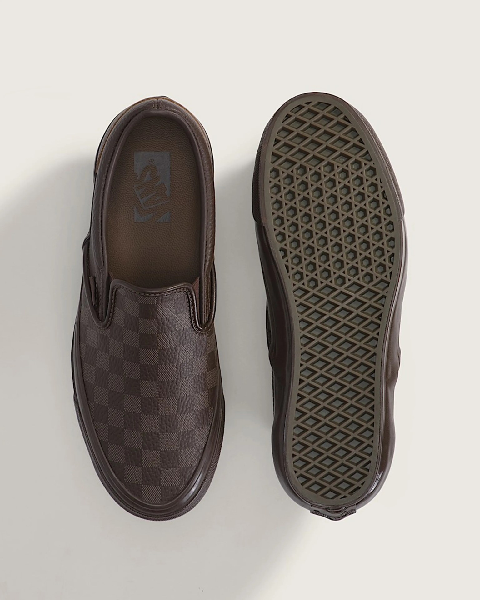 Pair of brown slip-on shoes with checkered pattern and waffle-patterned rubber soles.