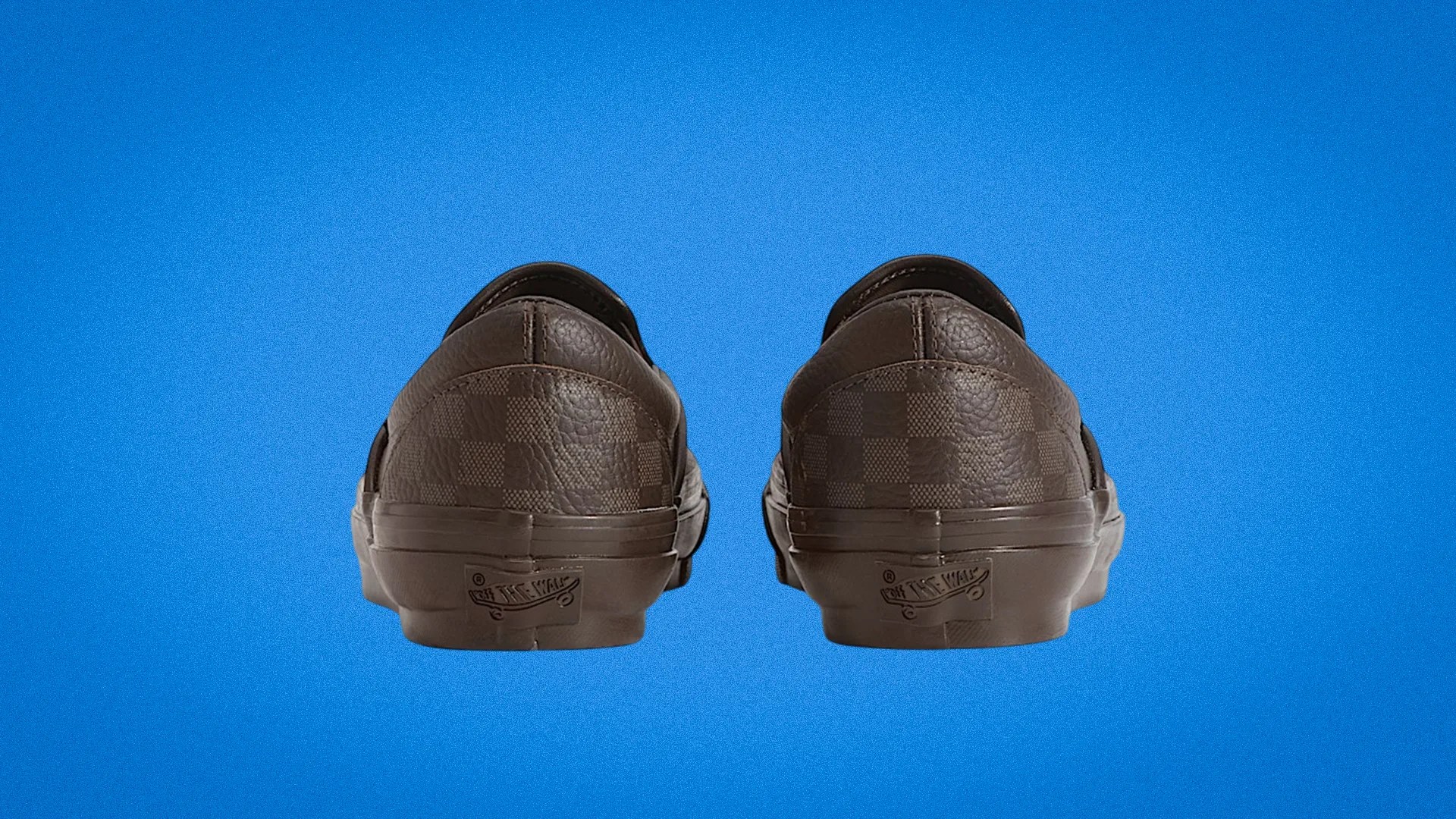 Pair of brown Vans slip-on shoes with checkerboard pattern shown from the back on a blue background.