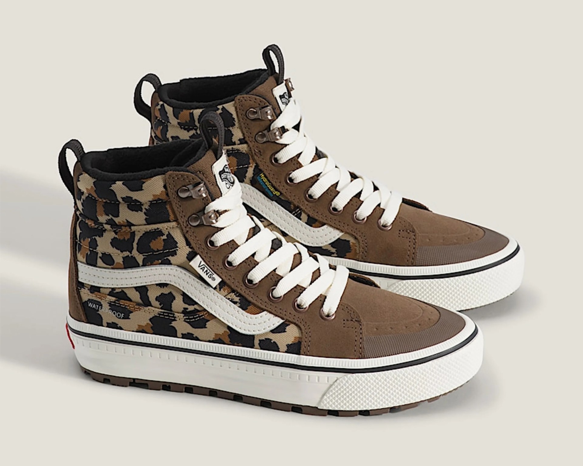 High-top Vans sneakers with brown suede, leopard print fabric, white laces, and white rubber soles.