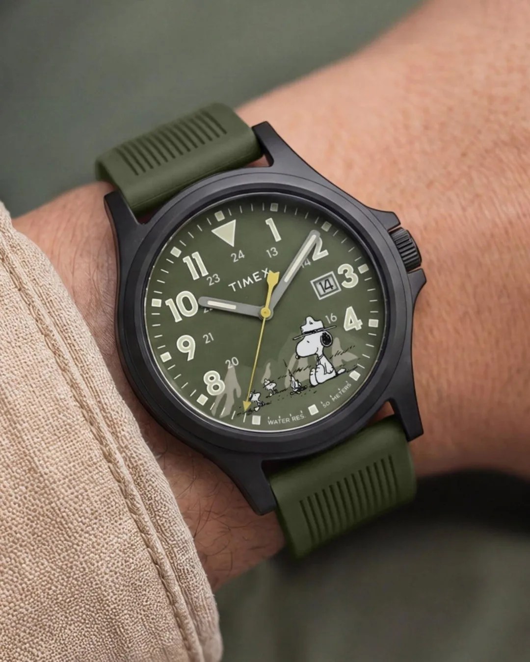 Timex wristwatch with black case, olive green dial and strap, featuring Snoopy and Woodstock characters.