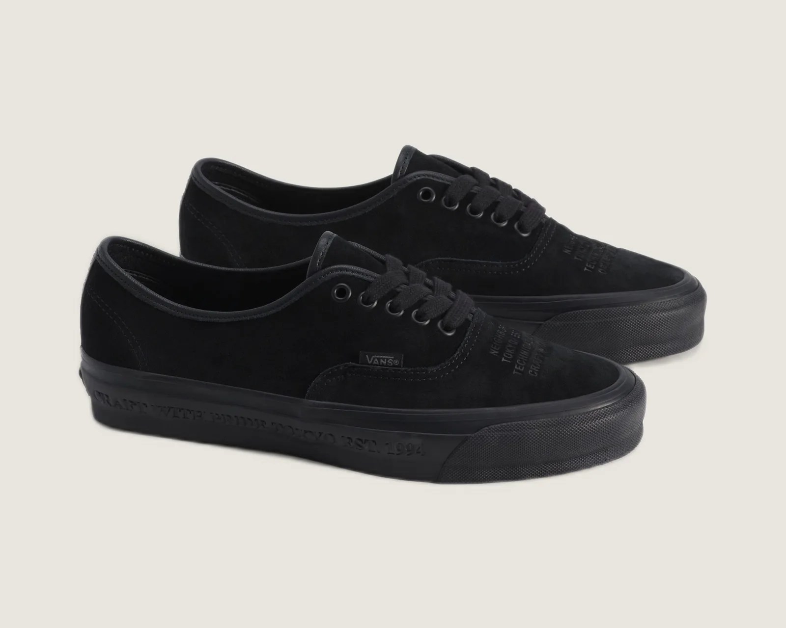 Pair of black Vans low-top sneakers with suede upper and embossed text on the toe and sole.