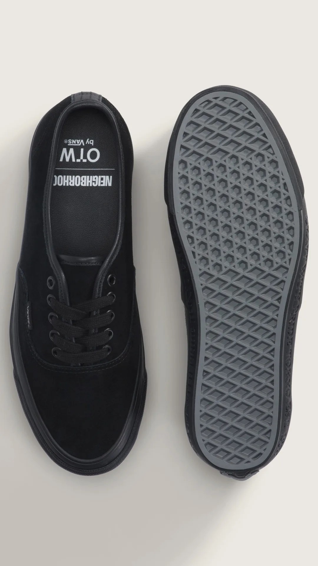 Pair of black low-top sneakers with black laces, one showing the top and the other showing the gray patterned sole.