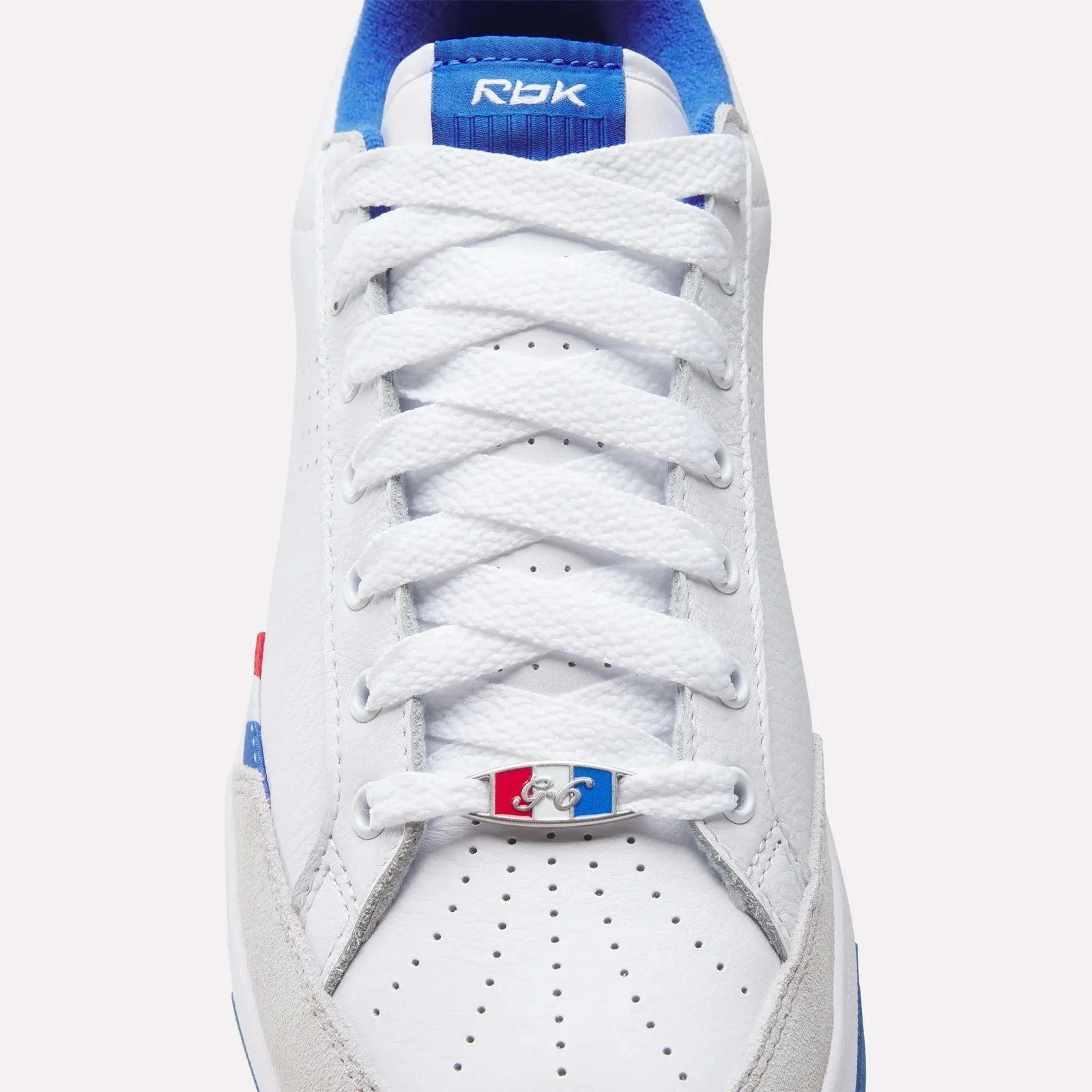 White leather sneaker with white laces, blue inner lining, and a red, white, and blue lace tag.