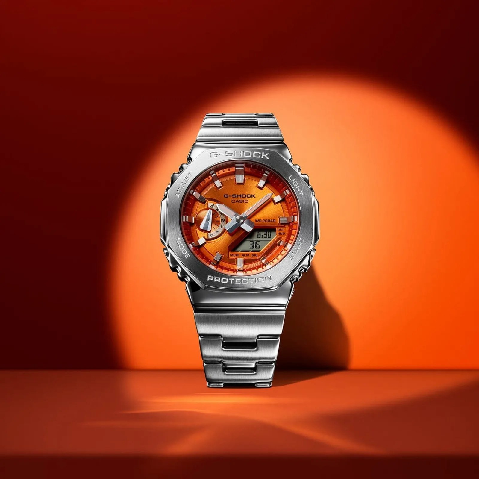 Silver metal G-Shock wristwatch with an orange dial and digital display on an orange background.