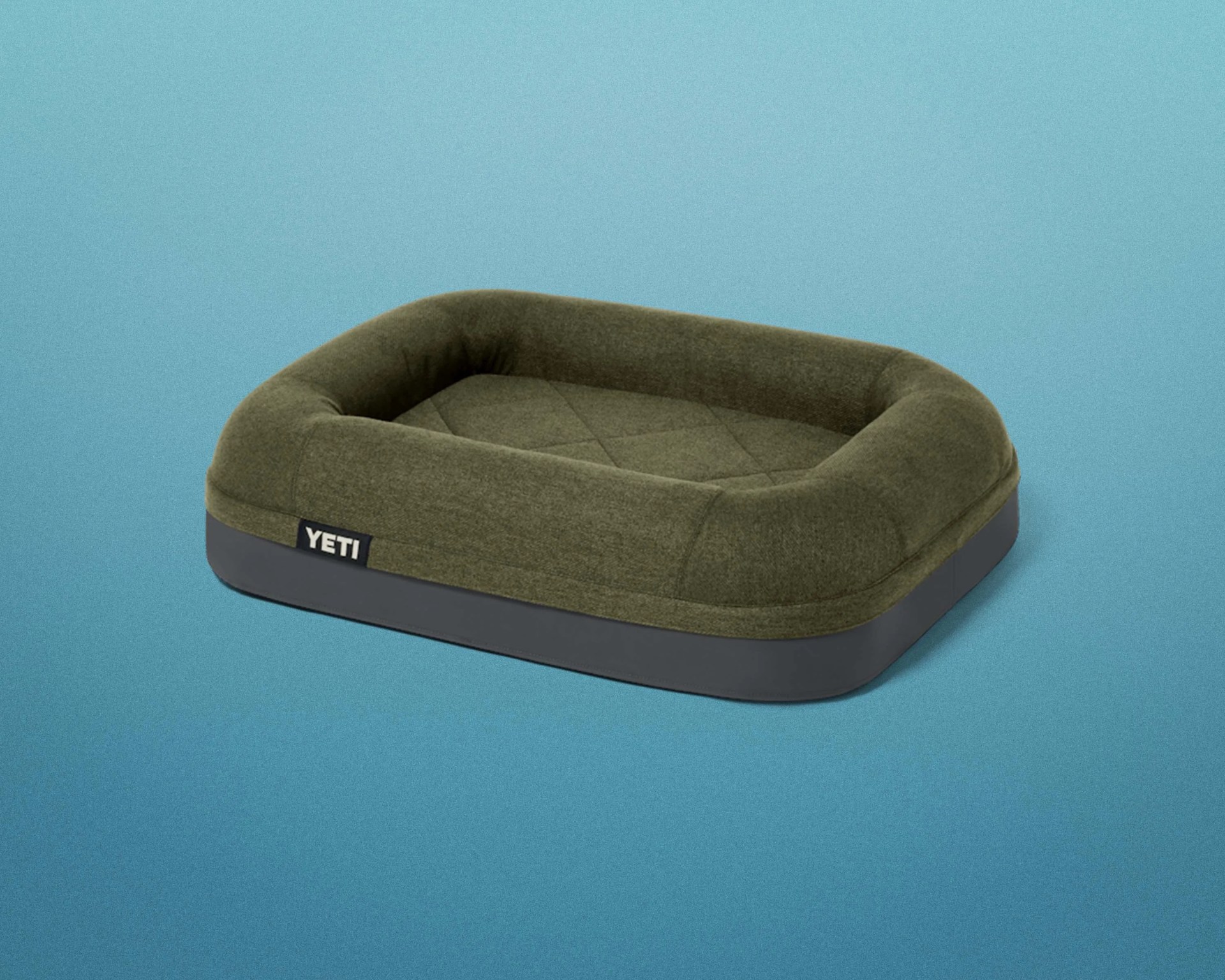 Olive green and dark gray rectangular pet bed with raised cushioned sides and YETI logo tag.